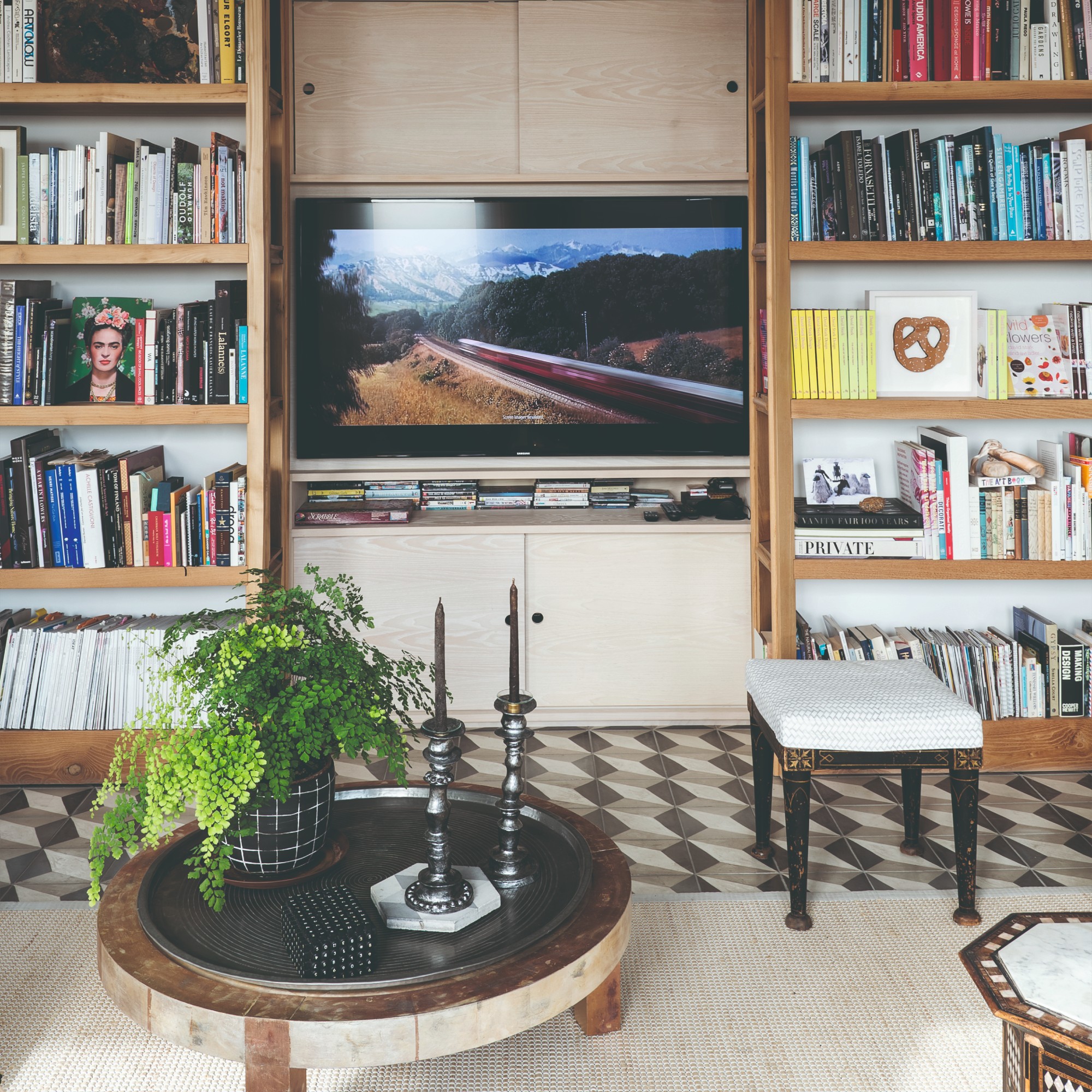 A living room with a TV media unit, bookcases on either side of it filled with books and a round coffee table