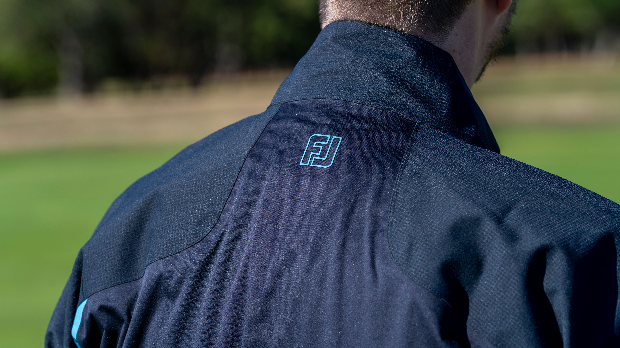 The view of a golfer wearing the FJ Arcus jacket from the back