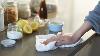 hand cleaning worktop with bicarbonate soda and lemons