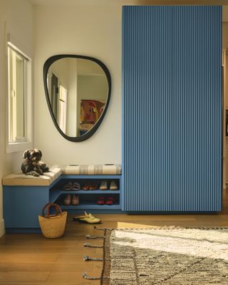 An entryway with blue built-in storage, wooden floors, and a tufted rug