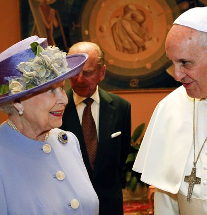 Queen Elizabeth wearing a purple coat and hat smiling at Pope Francis