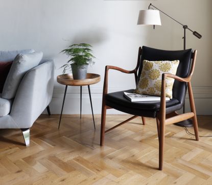 Armchair on a parquet floor with pale grey wall and sofa
