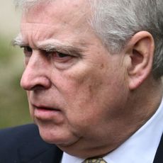 Prince Andrew wears a navy suit with a white shirt and looks pensive or annoyed