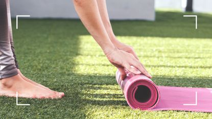 Woman wearing workout leggings rolling up Pilates mat on sunny roof terrace after doing Pilates every day