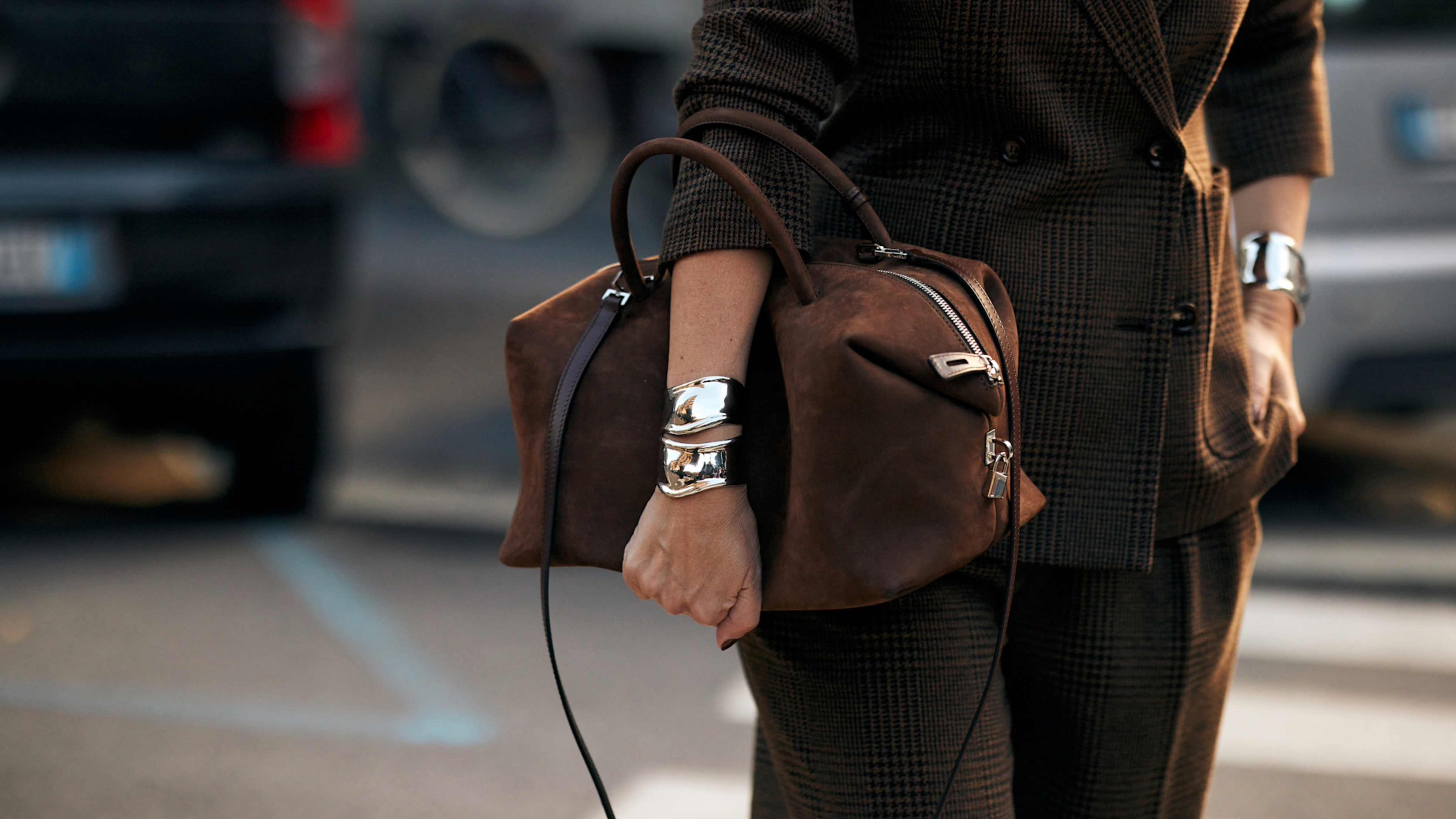 WOMAN carrying a brown suede bag with silver cuff bracelets