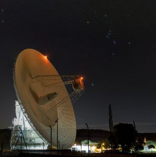 The 230-foot (70 meters) antenna of DSS-63 appears to point toward Sirius, the brightest star in the night sky. Above it and to the right shines the colorful winter constellation of Orion.
