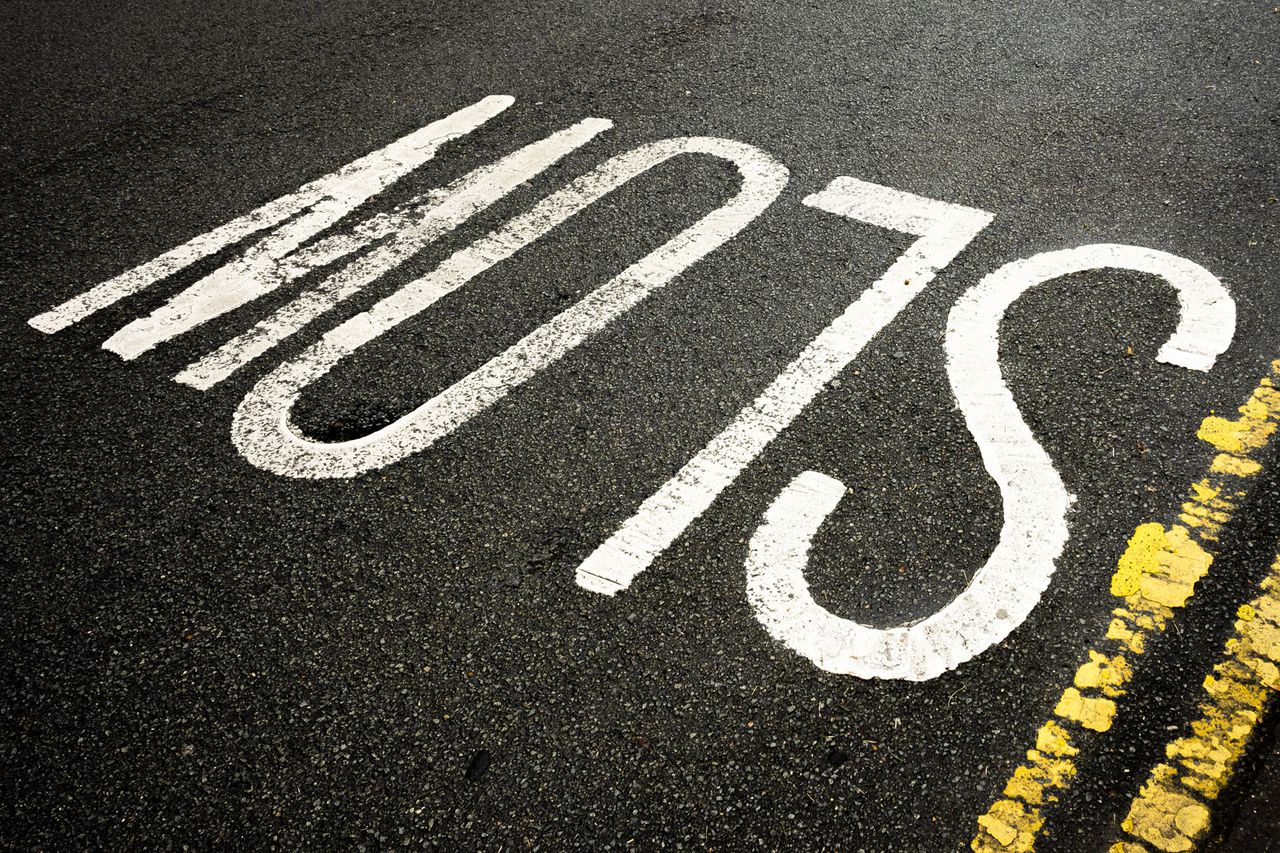A photograph of the word SLOW written on a road taken with the Nikkor Z DX 24mm f/1.7 lens