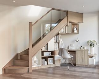 An under stairs ideas with built-in desk and shelving unit under pale wood staircase
