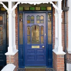 A blue front door with stained glass inserts and a white porch