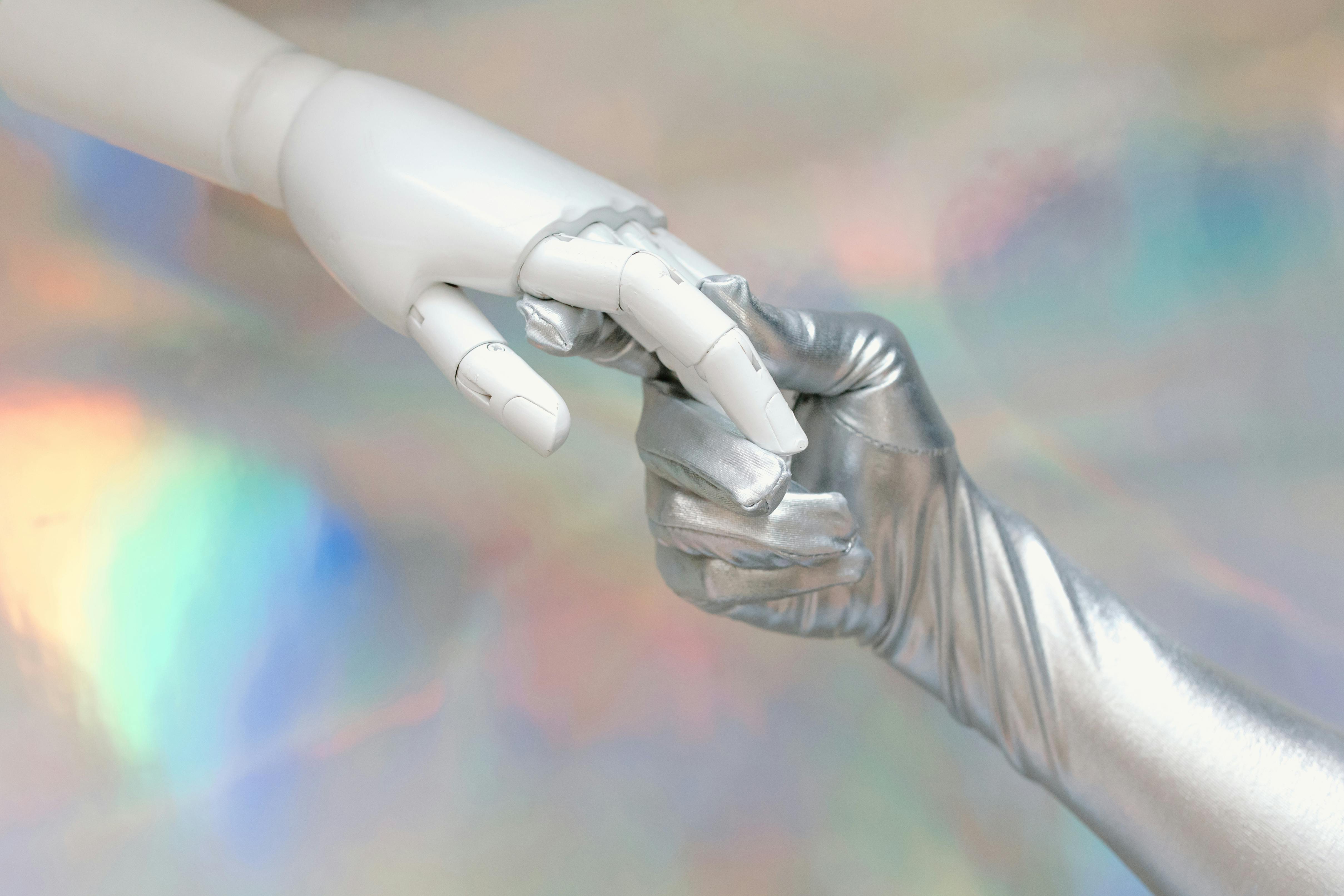 A robot hand grabs a hand with a silver glove. 