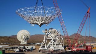 A crane lowers a giant NASA radio dish into place while building Deep Space Station 23 on Dec. 18, 2024.