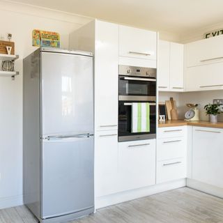 A white kitchen with a built-in oven and large fridge