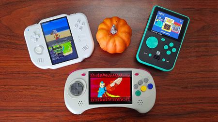 MagicX Zero 40 on left, Anbernic RG ARC-D in centre, and Super Pocket Taito Edition on right with pumpkin in the middle on woodgrain desk.