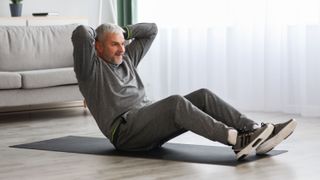 man on an exercise mat sitting up with his hands behind his head