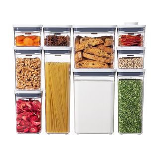 10 tall and short square food storage bins with air tight lid. They are stacked in this image and filled with dry goods such as walnuts, cookies, beans, flour, pasta and star anise