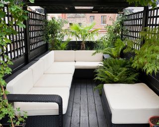 A black-and-white themed small backyard with rattan furniture and trellis