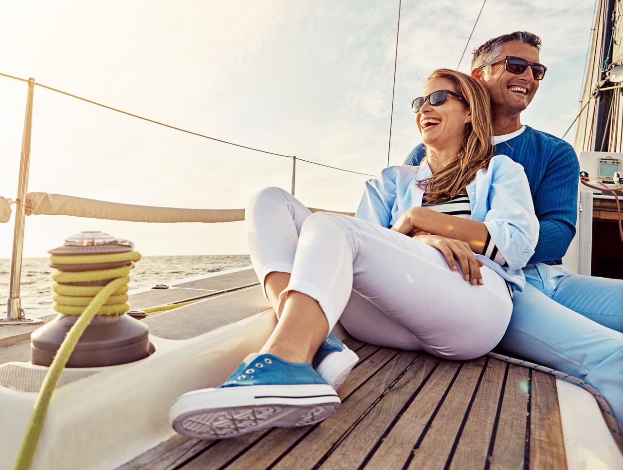 A happy middle-aged couple relaxes on on sailboat.