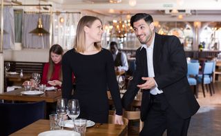Gentleman helps a woman sit down at a restaurant.