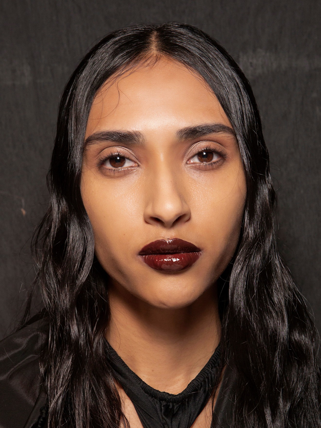 A model wearing a NYE makeup idea look complete with a bold burgundy lip.