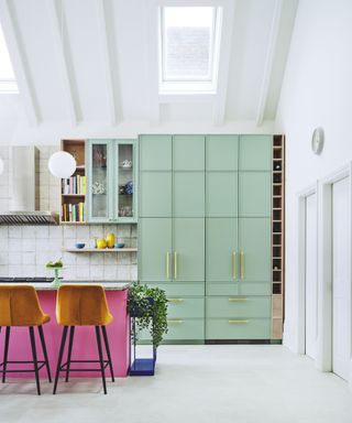 Colour block kitchen with bright pink island and mint green pantry