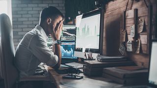 Man with head in hands looking at computer screen