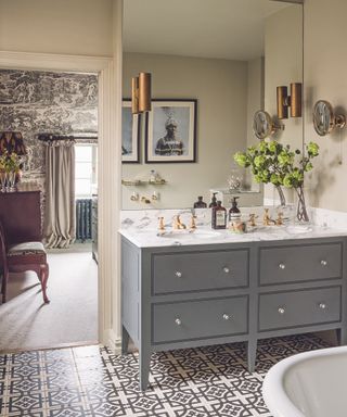 monochrome pattern on the wallpaper in the bedroom is complimented by a similarly colored pattern on the bathroom floor, and the rich copper hue on the lampshade is echoed by the bathroom lighting