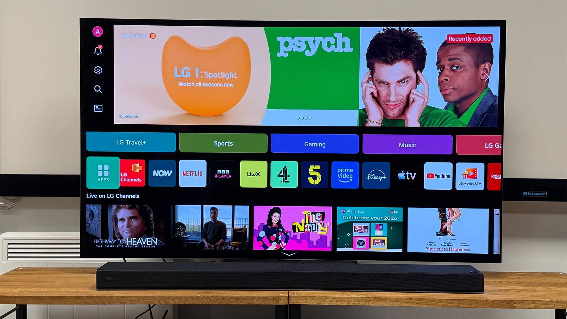 LG Sound Suite H7 soundbar on wooden AV rack underneath LG TV