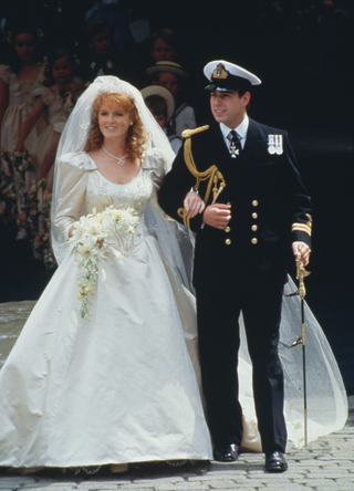 Sarah, Duchess of York, wearing an ivory-silk Lindka Cierach wedding dress, and Prince Andrew, Duke of York, wearing the ceremonial uniform of a Royal Navy lieutenant, arm-in-arm following their wedding ceremony at Westminster Abbey in London, England, 23rd July 1986