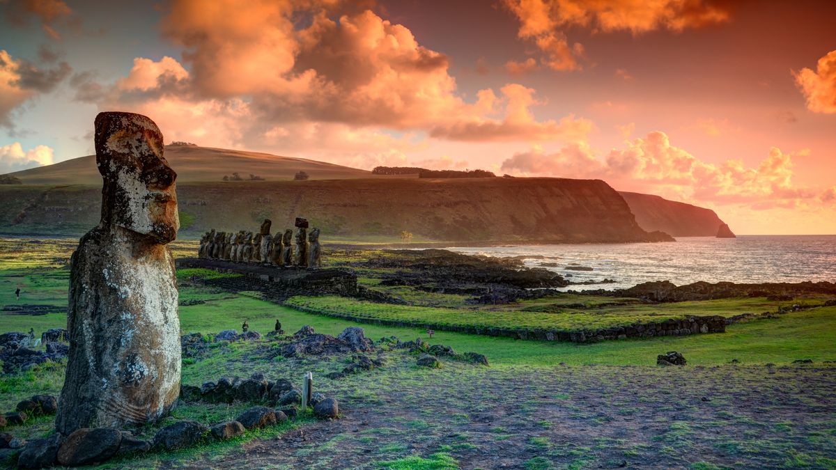 A moai statue at Tongariki with the Ahu Tongariki moai in the background on Easter Island. The newfound moai (not pictured here) was found buried at a dried up lake bed.