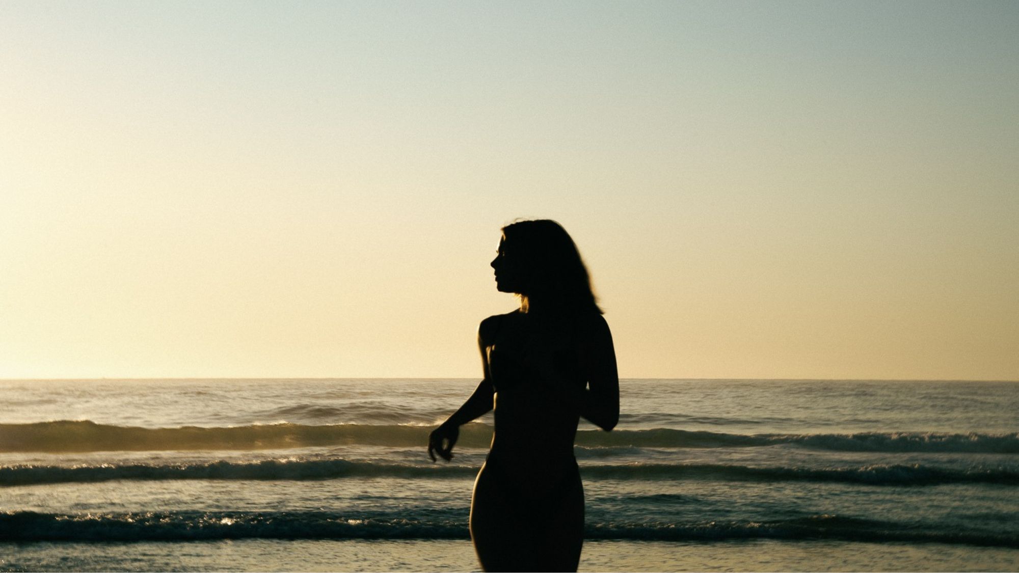 A woman running into the sunset on the beach
