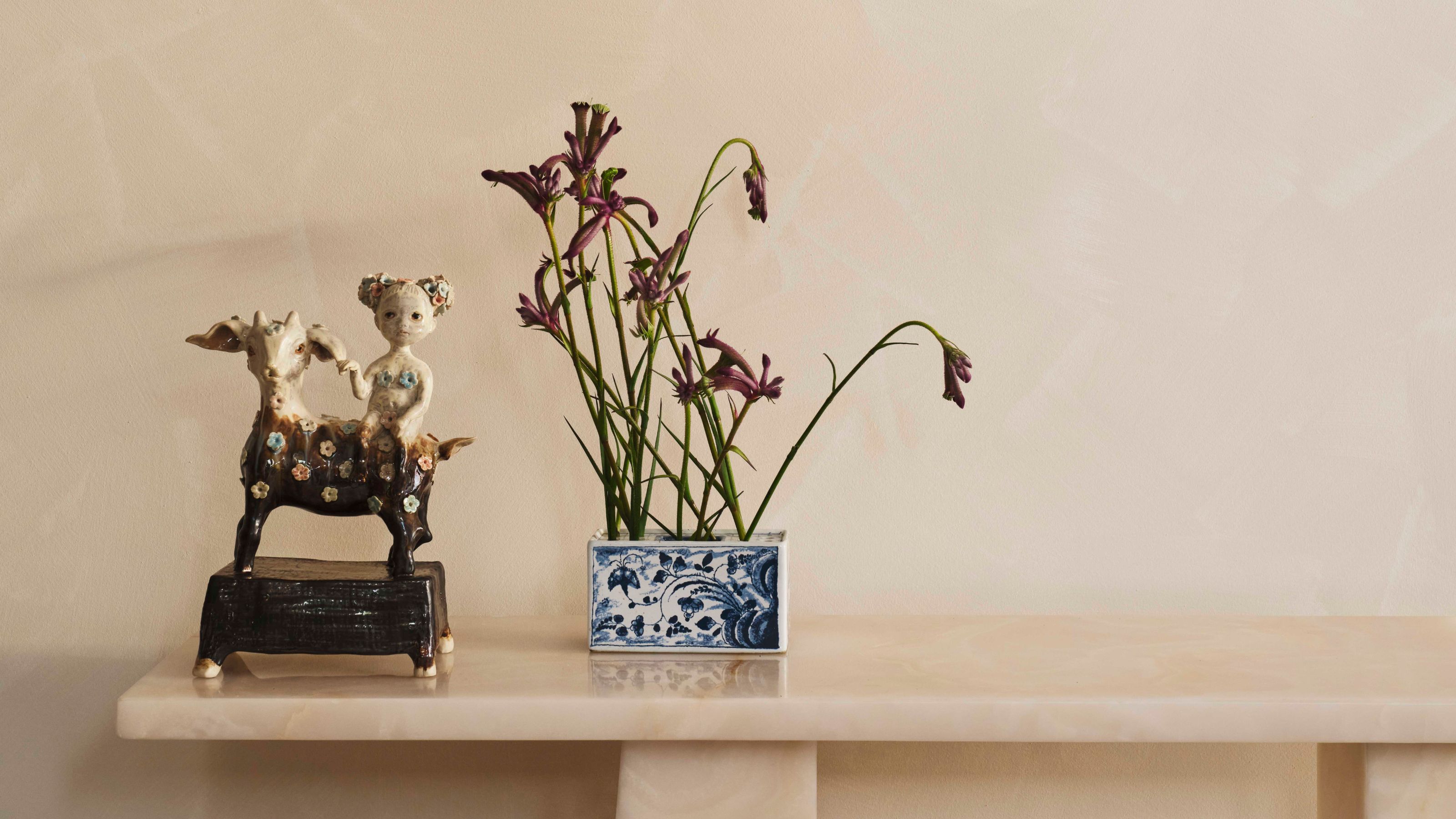 a sculpture and a tulipieres filled with flower stems sitting on a mantle