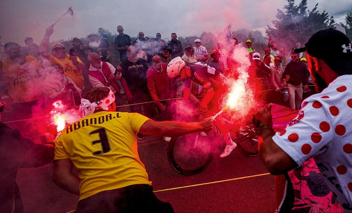 Fans welcome the Tour de France peloton with flares, creating a vibrant atmosphere along the roads of northern France.