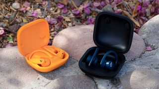 The orange Powerbeats Pro 2 next to the Navy original Powerbeats Pro.