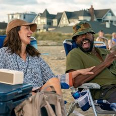 tina fey and colman domingo laughing on the beach in lawn chairs in a still from the four seasons season 2