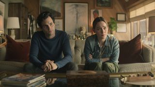 Joe und Love sitzen auf einer Couch und schauen nachdenklich und traurig in You Staffel 3 auf Netflix