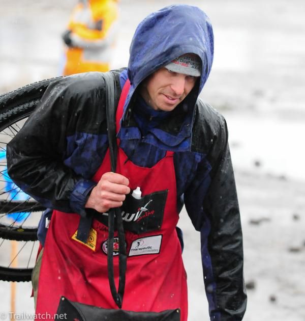 A mechanic heads to the pits with his rider's wheels