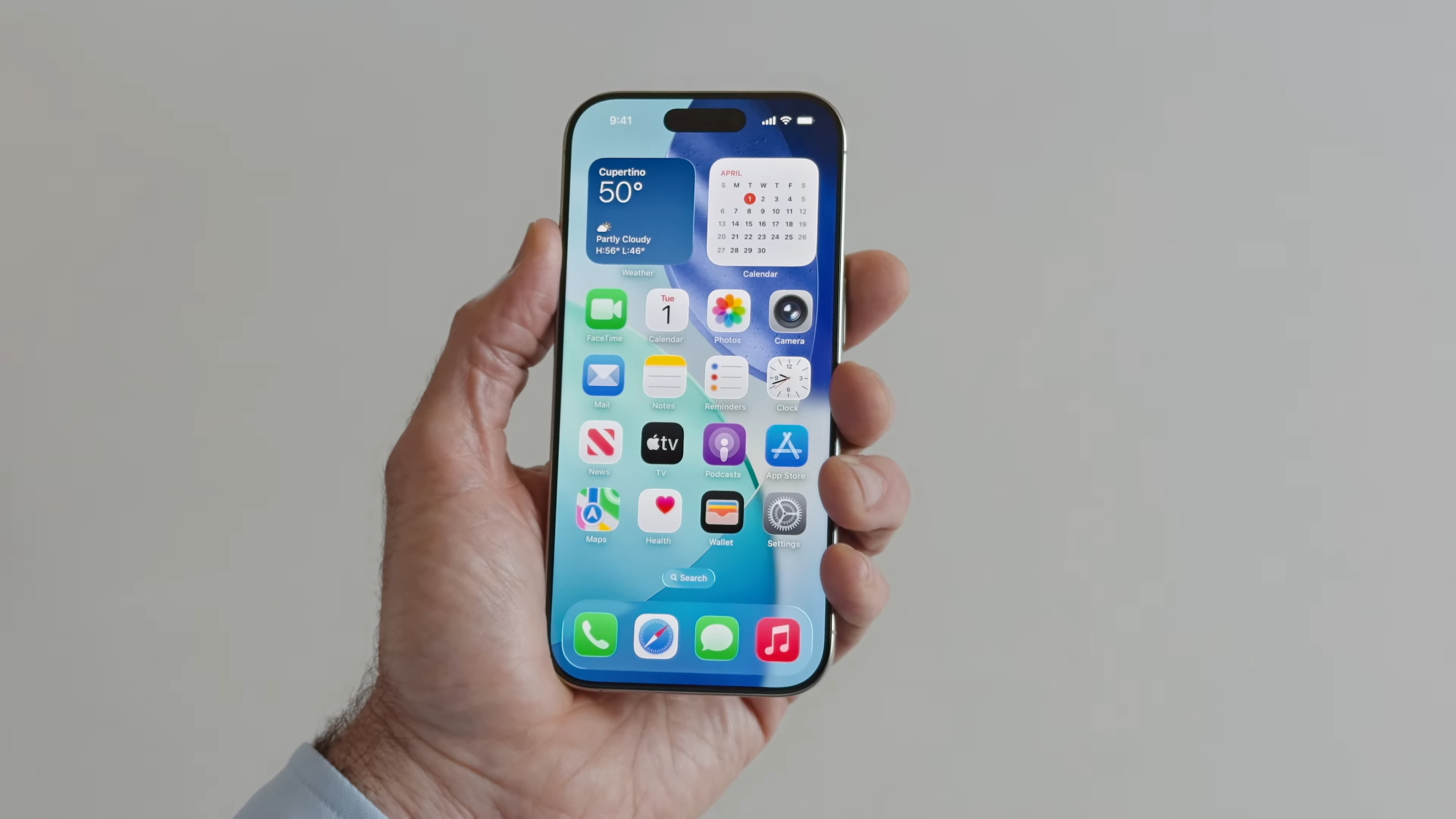 iPhone 16 Pro in hand showing iOS 26 homescreen at WWDC 2025.