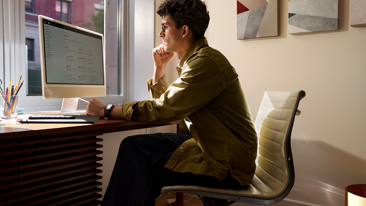 Man sitting at a home office desk working on computer.