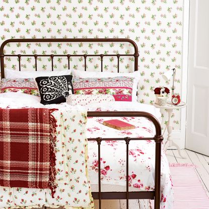 Bedroom with wrought iron bed and floral wallpaper