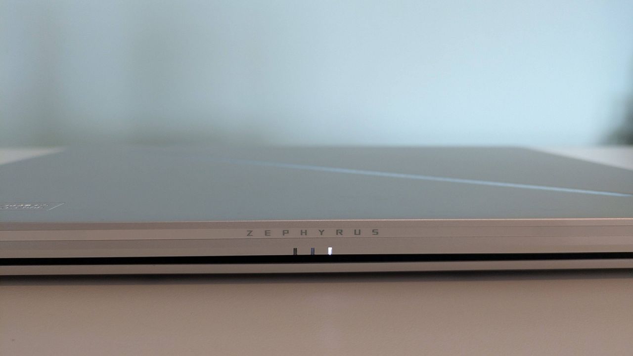 Close-up of Zephyrus logo on rear of Asus ROG Zephyrus G14 (2025), closed on desk with green background