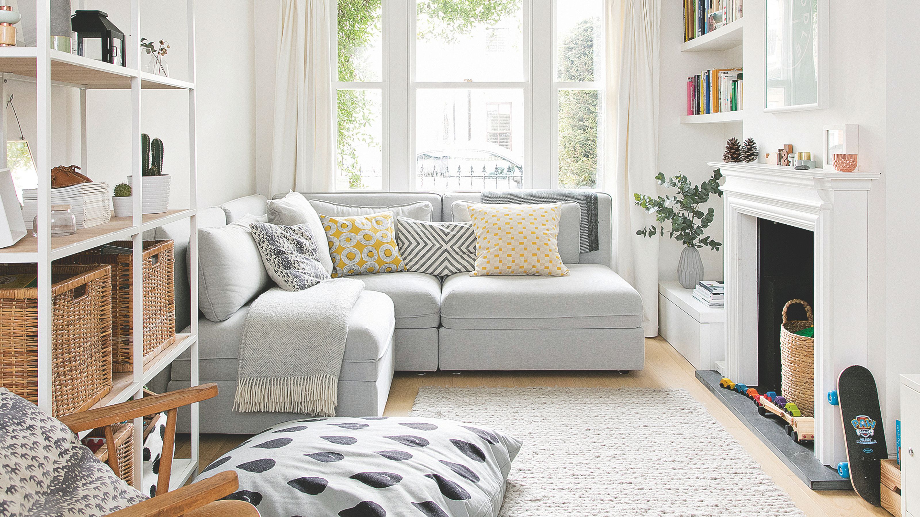 White living room with a grey sofa and everyday home items on the floor by a white fireplace
