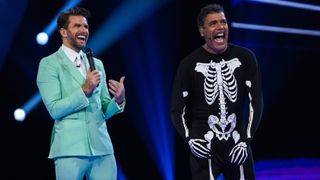 Joel Dommett standing with Chris Kamara who is wearing a skeleton costume after being revealed as Ghost
