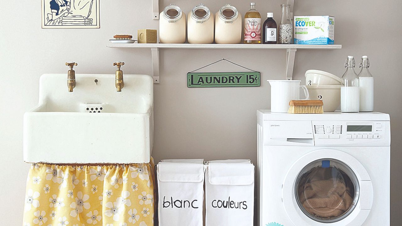 A laundry room with a washing machine, laundry baskets and detergents