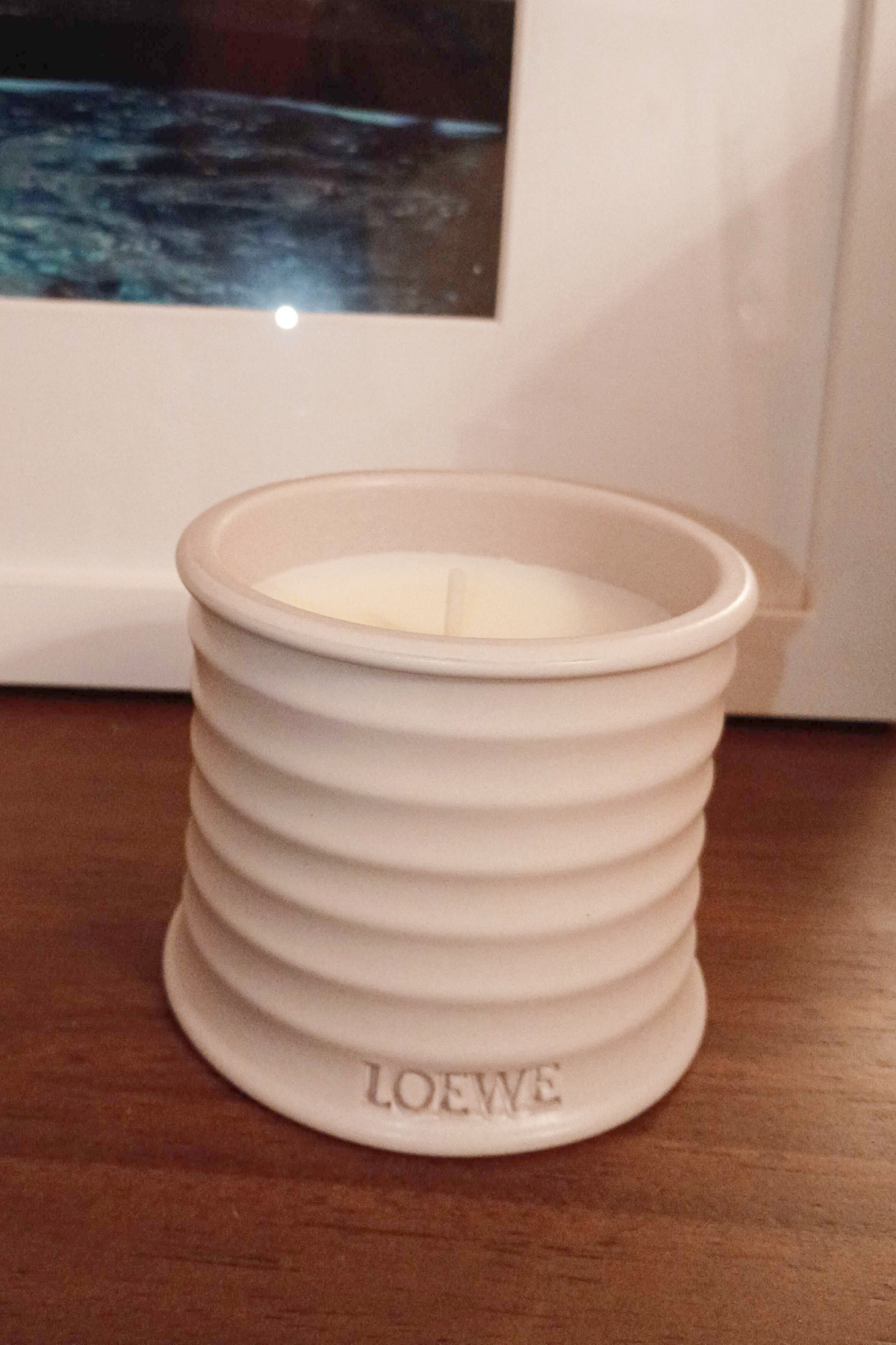 loewe oregano candle in a white vase on a wood background