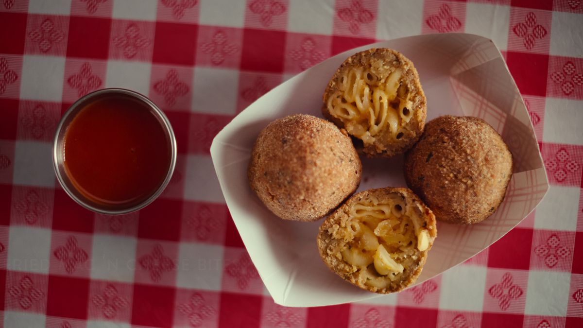 Image from Street Food: USA showing fried mac n cheese balls with a dip on a checkered red tablecloth.