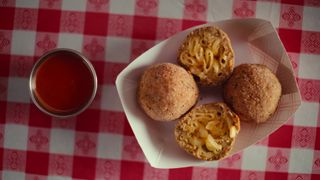 Image from Street Food: USA showing fried mac n cheese balls with a dip on a checkered red tablecloth.