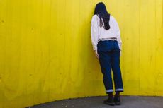 millennial woman leaning on yellow wall