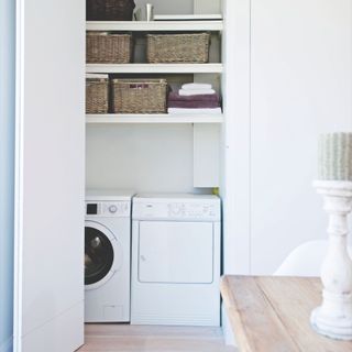 Sliding cupboard door with washing machine, tumble dryer, and other utility storage in it