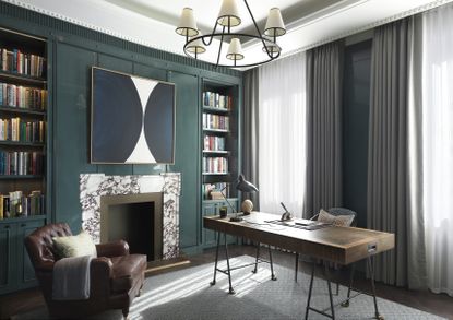 freestanding desk in large green room with chandelier and marble fireplace