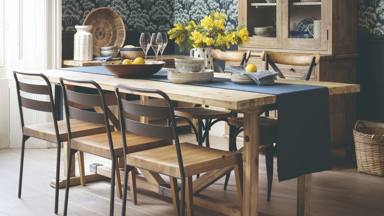 A dining room with a set table and a floral wallpaper